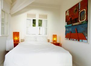 ein weißes Bett in einem weißen Schlafzimmer mit zwei Lampen in der Unterkunft TOUDOU DOUDOU in Deshaies