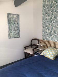 um quarto com uma cama azul e uma cadeira em gite Au Bout du Chemin em Le Pouget