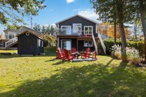 a house with red chairs in the yard at Impressive Modern Waterfront Home on Georgian Bay in Port McNicoll