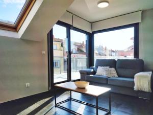a living room with a couch and a table at Desconectaengalicia Ático La Perla, piscina y pista tenis in Sanxenxo +26 photos
