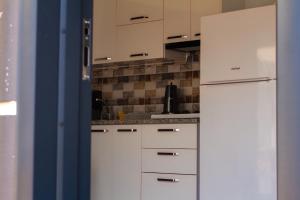 a kitchen with white cabinets and a white refrigerator at ADRASAN HİMERA APART & BUNGALOW in Adrasan