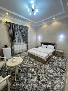 a bedroom with a large bed and a table and a tableasteryasteryasteryastery at Hotel Jasmina in Samarkand