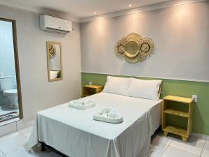 1 dormitorio con 1 cama con 2 toallas en Suíte beira mar no centro de maragogi en Maragogi