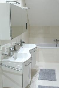 een witte badkamer met 2 wastafels en een bad bij Villa pod Szczeblem in Kasinka