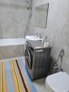 Un baño con lavabo, inodoro y espejo. en Апартаменты в новом доме, en Almaty