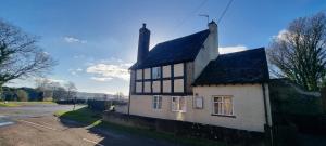 a white and black house with a black roof at Pass the Keys Malt House With Hot Tub Stunning Tudor Cottage in Craven Arms