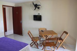 Cette chambre comprend une table, des chaises et une horloge murale. dans l'établissement Kitnet Apto em Cabo Frio RJ - Recanto das Corujas, à Cabo Frio