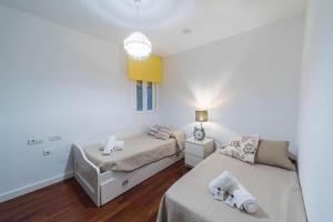 a white room with two beds and a lamp at Expoholidays - Javier Sanz in Almería