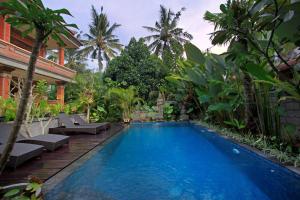 a swimming pool in the middle of a yard with palm trees at Tanah Semujan Ubud in Ubud
