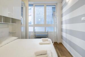 una camera da letto con un letto bianco con due asciugamani di Easylife - San Babila - Elegante e rifinito bilocale nel cuore della città a Milano