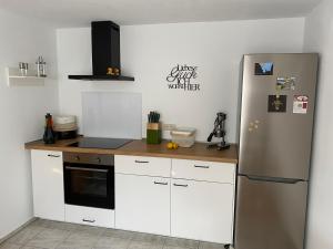 cocina con armarios blancos y nevera de acero inoxidable en Schwarzwaldglück Apartment en Oberried