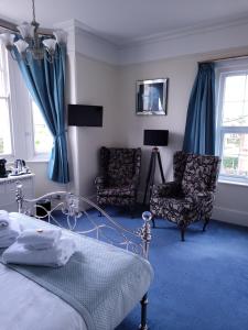 a bedroom with a bed and two chairs at The Birdham At Bembridge in Bembridge