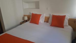 1 dormitorio con 1 cama con almohadas de color naranja y blanco en Al-Xelb guesthouse, en Silves