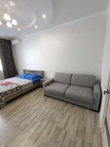uma sala de estar com um sofá e uma cama em 1 комнатная квартира ЖК Альтаир по ул.Байшева 7а em Aqtöbe