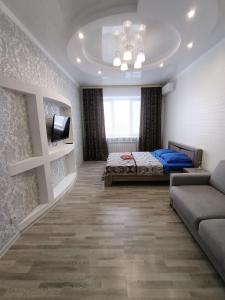 um quarto com uma cama, um sofá e uma televisão em 1 комнатная квартира ЖК Альтаир по ул.Байшева 7а em Aqtöbe