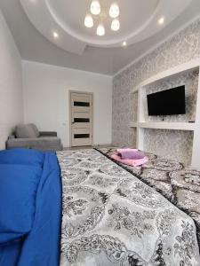 um quarto com uma cama grande e uma televisão de ecrã plano em 1 комнатная квартира ЖК Альтаир по ул.Байшева 7а em Aqtöbe