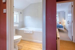 a bathroom with a tub and a toilet and a bed at Ivy House Mells in Halesworth