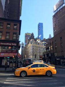 un coche amarillo está conduciendo por una calle de la ciudad en NYC Empire Apartments, en Nueva York