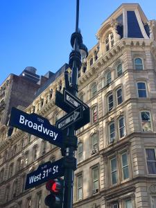 a traffic light with street signs in front of a building at NYC Empire Apartments in New York