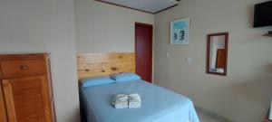 um quarto com uma cama com lençóis azuis e uma cómoda em Pousada Gabriel em Praia de Araçatiba