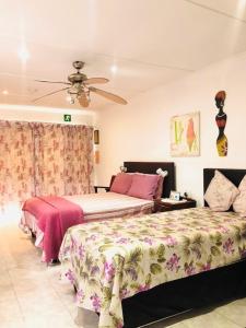 a bedroom with two beds and a ceiling fan at JoThams Bed & Breakfast or Self-catering in Durban
