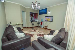 a living room with two brown leather couches and a kitchen at Stunning 2-Bed Apartment in Moshi Town in Moshi
