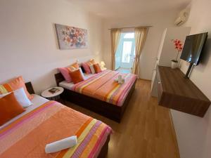 Cette petite chambre comprend deux lits et une télévision. dans l'établissement Apartments Kovač, à Makarska