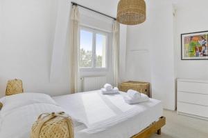 Maison de l'Ermitage - Welkeys في لو بوسكا: غرفة نوم بيضاء مع سرير عليه مناشف