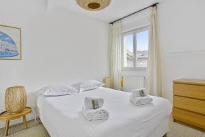 Un dormitorio con una cama blanca con toallas. en Maison de l'Ermitage - Welkeys, en Le Bouscat
