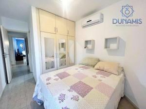 um quarto com uma cama com uma colcha em Guaruja Pitangueiras no Guarujá