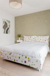 - un lit blanc orné de fleurs dans la chambre dans l'établissement Bardolino Suite, à Bardolino