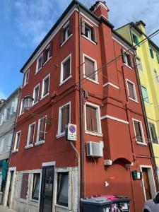 ein rotes Gebäude auf der Straßenseite in der Unterkunft Appartamento Vale Mare Vista Canale in Chioggia