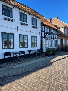 a white building with tables and chairs in front of it at Restaurant Sælhunden in Ribe