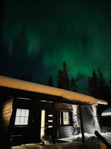 a cabin with the green northern lights in the sky at Chalé NAAVA in Rukatunturi 