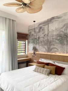 1 dormitorio con 1 cama grande y ventilador de techo en Exclusive beachfront apartment en Belle Mare