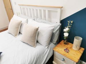 Un dormitorio con una cama blanca con almohadas y una mesa en The Bakery, en Pilling