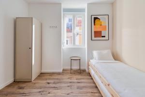 Dormitorio blanco con cama y taburete en Golden Setubal, en Setúbal