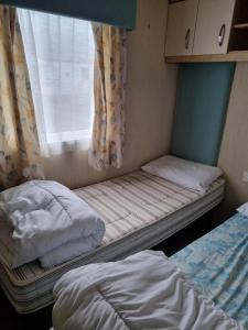 two beds in a small room with a window at Caravan L16 in Mablethorpe