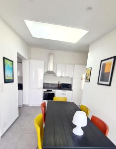 a kitchen with a black table and yellow chairs at MAGNIFIQUE APPARTEMENT T4 GRAND STANDING - VUE MER PANORAMIQUE ET PISCINE in Bandol