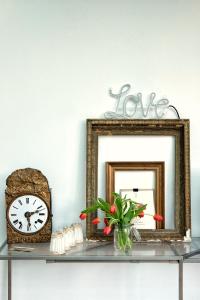 een plank met twee spiegels en een klok en een vaas met bloemen bij LA MAISON d'HORTENSE, maison de charme et de caractère in Toulouse