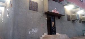 un edificio con una puerta con un cartel. en تحتمسنا كا بيت تحتمس house of tohotms en Nag` el-Qabba