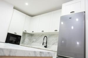 cocina con armarios blancos y nevera de acero inoxidable en Precioso apartamento en Jaén a 70 m de la Catedral en Jaén