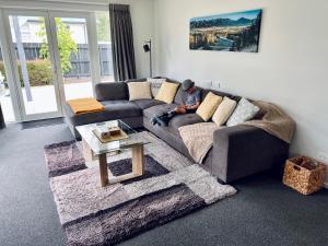 a man sitting on a couch in a living room at Cottage on Harrogate in Hanmer Springs