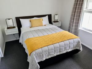 a bedroom with a large bed with a yellow blanket at Cottage on Harrogate in Hanmer Springs