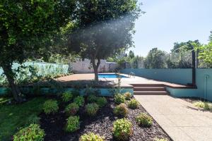 un giardino con piscina, alberi e recinzione di Oporto Swimming Pool House a Porto