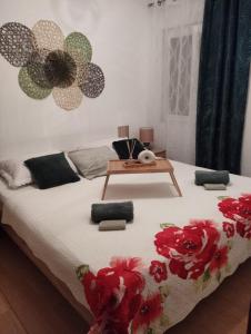 ein Bett mit einem Tisch und roten Blumen drauf in der Unterkunft Apartmani Bilić in Dugi Rat