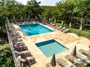 - une vue sur la piscine bordée de chaises et de parasols dans l'établissement Le Bois d'Imbert, à Rocamadour