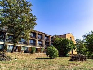 um prédio de apartamentos com uma árvore em frente em Le Bois d'Imbert em Rocamadour