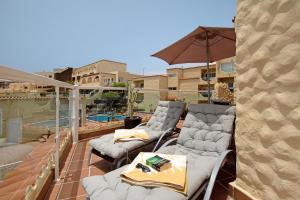 a patio with three chairs and an umbrella at Relax y confort en Costa Calma in Pájara