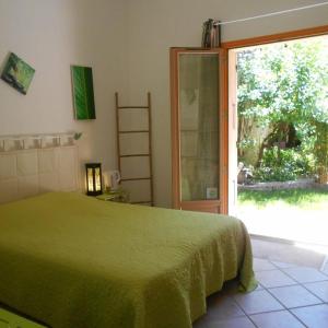 um quarto com uma cama verde e uma porta de vidro deslizante em Louminai em Donzère